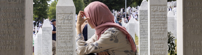 Eine Frau kniet am Mahnmal von Srebrenica.