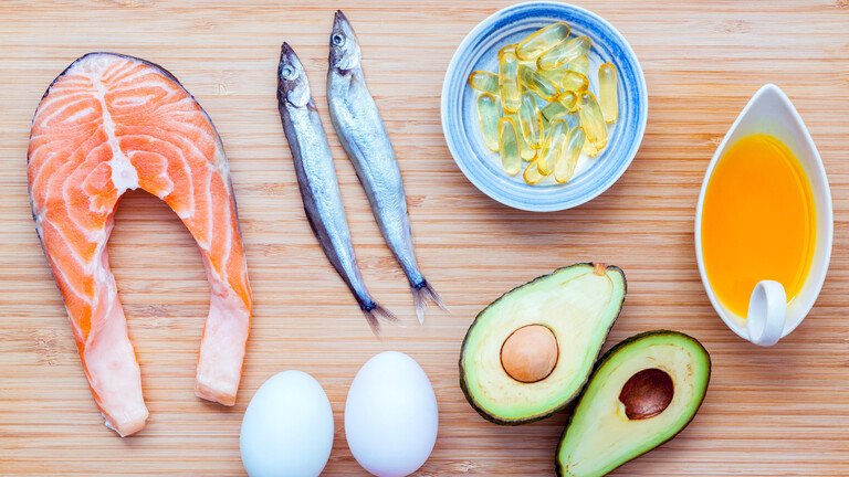 Lachs, Shishamo-Fisch, Fischöl, Avocado und Eier liegen auf einem Bambus-Schneidebrett