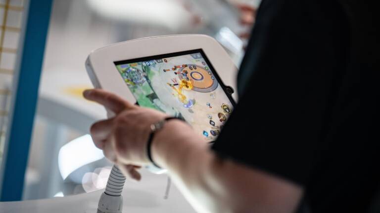 Eine Person testet ein Computerspiel an einem Tablet in der Kölner Messehalle während der Gamescom 2025.