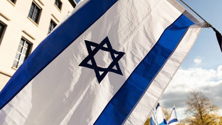 Die Flagge Israels weht bei sonnigem Herbstwetter.