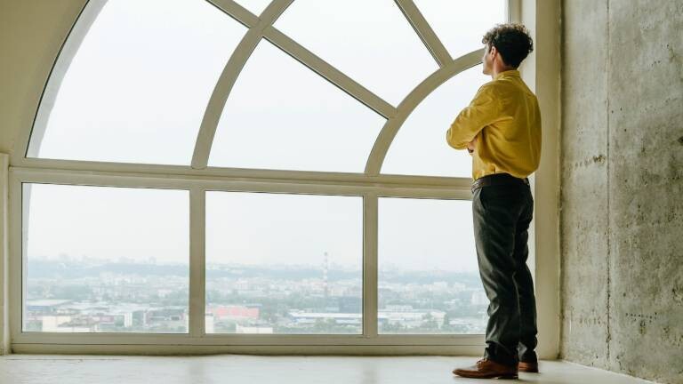 Ein Mann steht in einem Gebäude und schaut aus dem Fenster