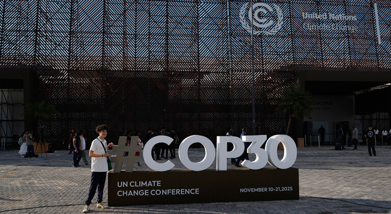 Eine Person posiert am Samstag, dem 8. November 2025, in Belém, Brasilien, für ein Foto vor einem Schild des UN-Klimagipfels COP30.