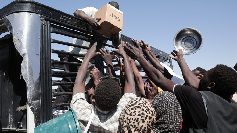 Im Sudan versammeln sich Menschen vor einem Lastwagen von humanitären Helfern.