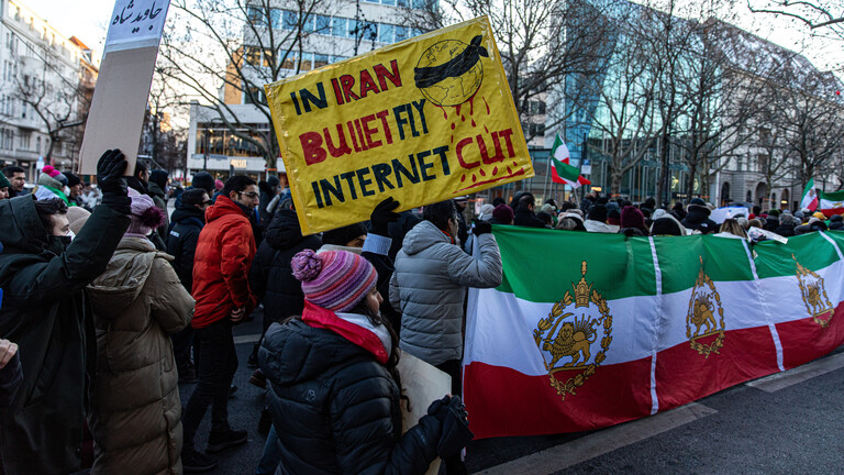 Bei einer Demonstration in Berlin gegen das Regime im Iran halten Demo-Teilnehmende ein Schild hoch mit der Aufschrift "In Iran bullet fly – Internet cut".