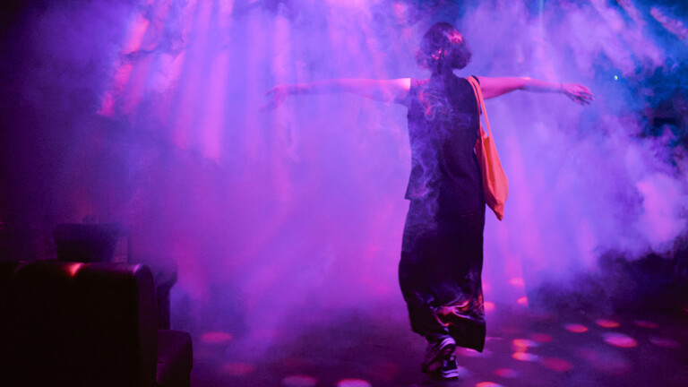 Eine Person tanzt im Licht und Neben in einem Club