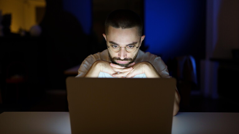 Mann schaut nachdenklich auf Laptop