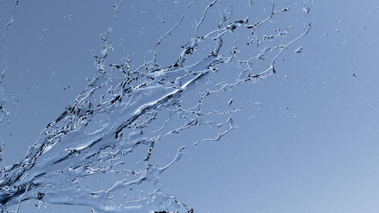 Spritzendes Wasser vor blauem Hintergrund