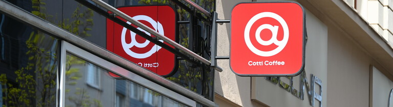 Schild der Kaffeekette Cotti Coffee an einer Hausfassade - ein weißes @-Zeichen auf rotem Grund