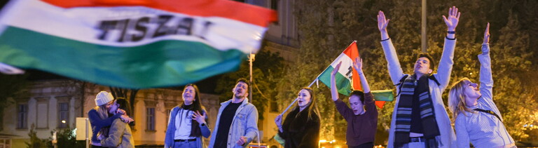 Junge Leute stehen auf einer Mauer und schwenken Ungarn-Flaggen nach dem Wahlsieg von  Péter Magyar (Budapest 13.04.2026)