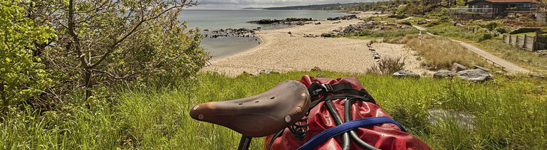 Fahrrad steht auf einem Hügel mit Blick auf Sandstrand und Meer
