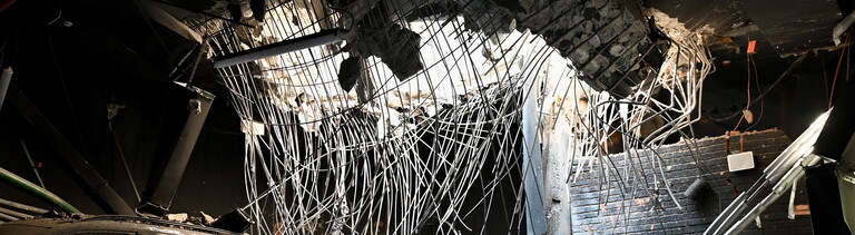 Kiew, Ukraine: Ein Loch in einer Geschossdecke durch eine Raketenexplosion und beschädigte Autos auf dem Parkplatz eines Wohngebäudes, das durch einen massiven russischen Raketenangriff beschädigt wurde.