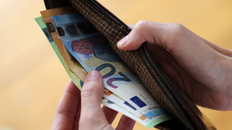 Geldscheine werden aus einem Porte­mon­naie entnommen.