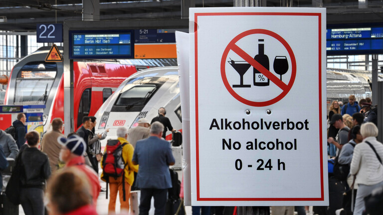 Fotomontage: Menschen in einem Bahnhof, großes Schild „Alkoholverbot 0-24h“ / Die Deutsche Bahn will kuenftig an allen Bahnhoefen ein Alkoholverbot durchsetzen.