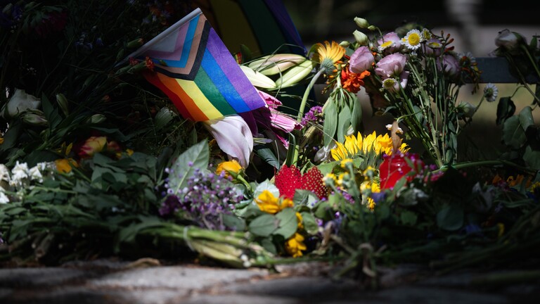 Blumen und eine Regenbogenflagge zum Gedenken an das Attentat beim Berliner CSD