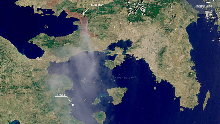 Die Waldbrände nähe Athens in einer Satellitenaufnahme: Es sind Umrisse Griechenlands mit Ausschnitten des Mittelmeers, eine braune Fläche und Rauchschwaden zu erkennen.