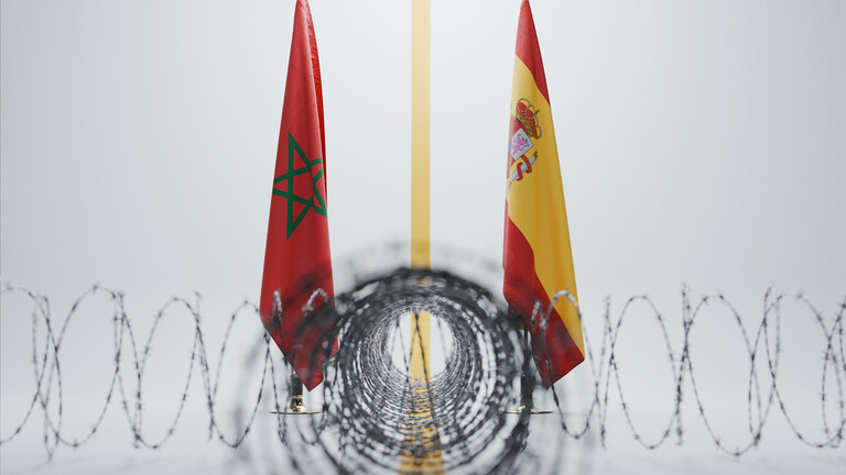 Die Flaggen von Marokko und Spanien, getrennt durch eine gelbe Linie hinter scharf gewundenem Stacheldraht vor weißem Hintergrund.