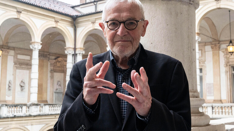 Der Physiker Francis Halzen gestikuliert mit seinen Händen und blickt direkt in die Kamera. Er trägt eine Brille und ein schwarzes Jakett.