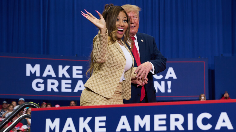 US-Präsident Donald Trump hilft der ins Publikum lachenden und winkenden Nicki Minaj bei einer Wahlkampfveranstaltung im McMorran Place Sports and Entertainment Center am Sonntag, dem 25. Oktober 2026, in Port Huron, Michigan, auf die Bühne.