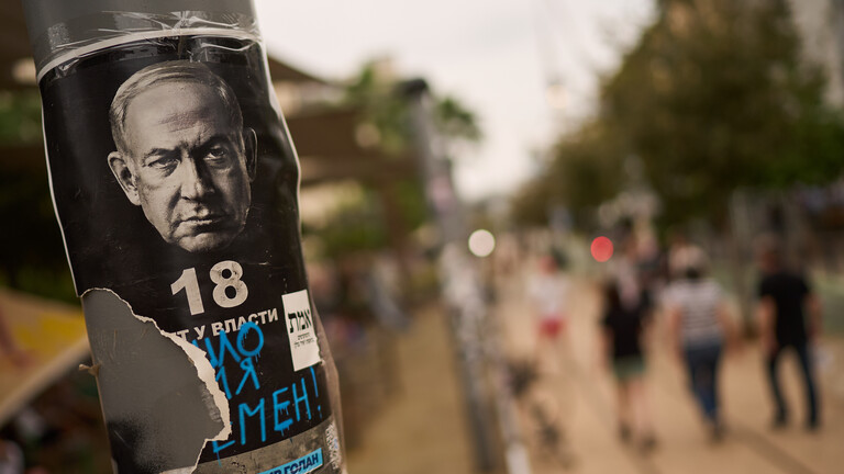 Ein überkritzelter und halb abgerissener Handzettel mit dem Bild des israelischen Ministerpräsidenten Benjamin Netanjahu ist an einem Straßenlaternen-Masten auf einem Gehweg in Tel Aviv mit Klebeband festgeklebt.