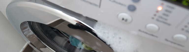 Schaum tritt aus einer geschlossenen Waschmaschine