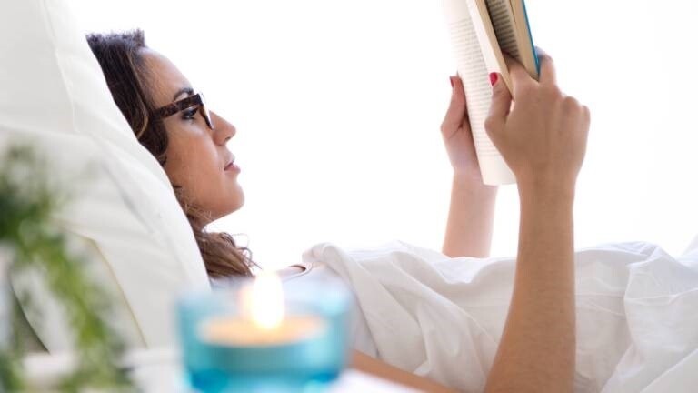 Eine Frau liegt im Bett und liest ein Buch