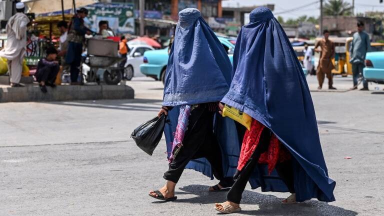 Zwei in eine blaue Burka gehüllte Frauen gehen über eine Straße in Jalalabad, Afghanistan (21.04.2025)