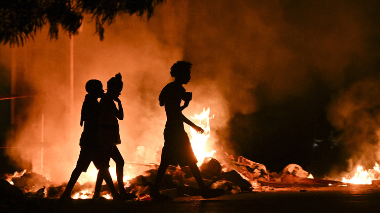 Kubaner gehen an einem Feuer vorbei, das von Demonstranten während eines Protests gegen den Mangel an Energie und Stromausfälle im Viertel Lawton in Havanna am 14. Mai 2026 gelegt wurde.