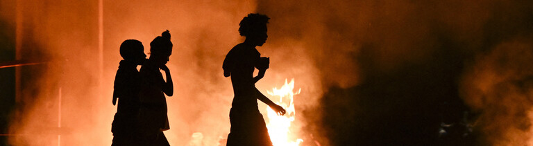 Kubaner gehen an einem Feuer vorbei, das von Demonstranten während eines Protests gegen den Mangel an Energie und Stromausfälle im Viertel Lawton in Havanna am 14. Mai 2026 gelegt wurde.