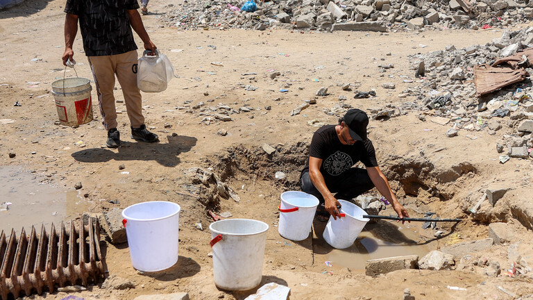 Ein Mann füllt Eimer mit Wasser, das aus den Restbeständen unterirdischer Leitungen in einem Lager für Kriegsvertriebene im Stadtviertel Sheikh Radwan in Gaza-Stadt geschöpft wird (06.07.2026)