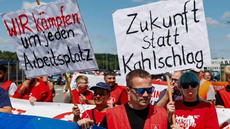 Mitarbeiter von Volkswagen (VW) halten bei einer von der IG Metall organisierten Kundgebung Schilder mit den Aufschriften „Wir kämpfen um jeden Arbeitsplatz“ (links) und „Zukunft statt Kahlschlag“ in die Höhe (9.07.2026, Zwickau)