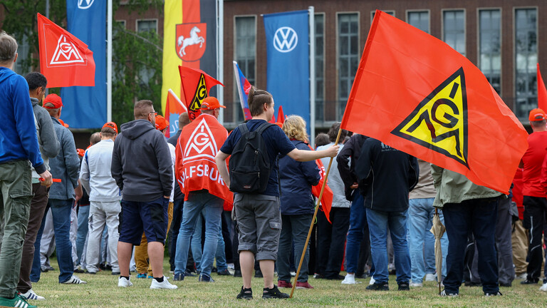Mitarbeiter von Volkswagen stehen mit Fahnen der Gewerkschaft IG Metall bei einer Kundgebung gegen Umstrukturierungen und Pläne für massiven Stellenabbau am VW-Stammsitz im Volkswagenwerk Wolfsburg (9.07.2026)