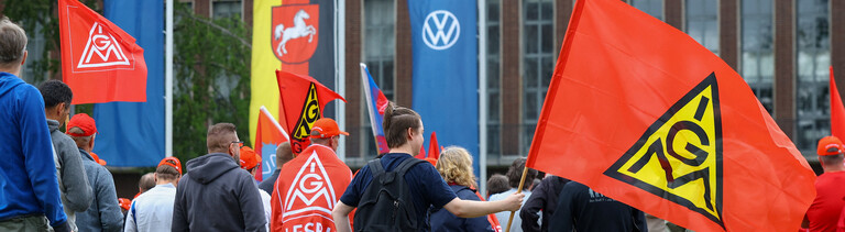 Mitarbeiter von Volkswagen stehen mit Fahnen der Gewerkschaft IG Metall bei einer Kundgebung gegen Umstrukturierungen und Pläne für massiven Stellenabbau am VW-Stammsitz im Volkswagenwerk Wolfsburg (9.07.2026)