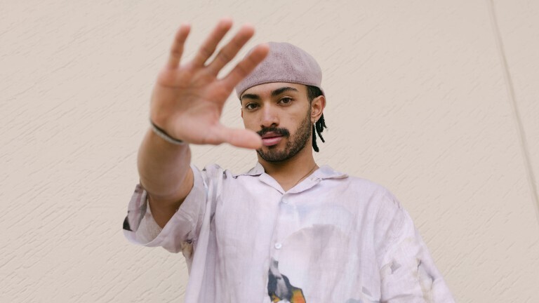 Ein Mann schaut in die Kamera und hält dabei seine ausgestreckte Hand vor sich.