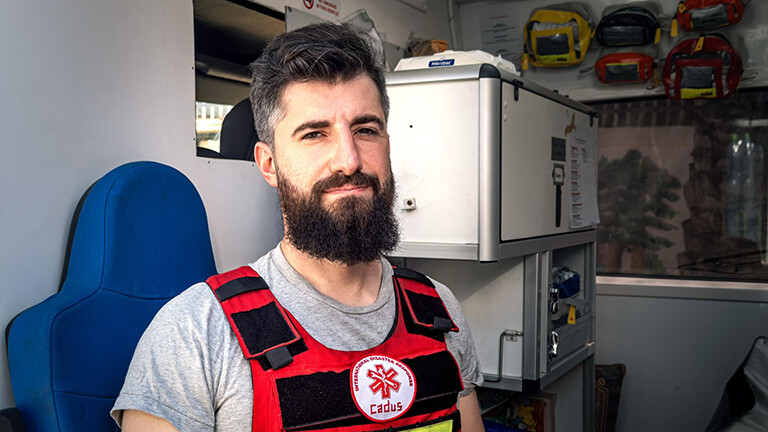 Portrait des Arztes Amar Mardini, der für die Hilfsorganisation Cadus im Gazastreifen arbeitet, in Schutzweste in einem Krankenwagen, der