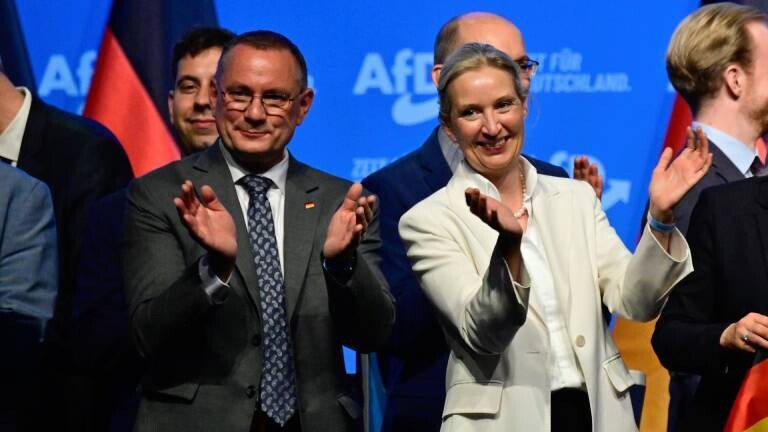 Alice Weidel (rechts), die Co-Vorsitzende der Partei Alternative für Deutschland (AfD), steht am zweiten Tag des Parteitags auf dem Messegelände Erfurt neben Tino Chrupalla in einer Menge von AfD-Mitgliedern und applaudiert.