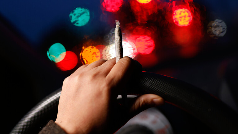 Eine Hand am Steuer mit einem Joint