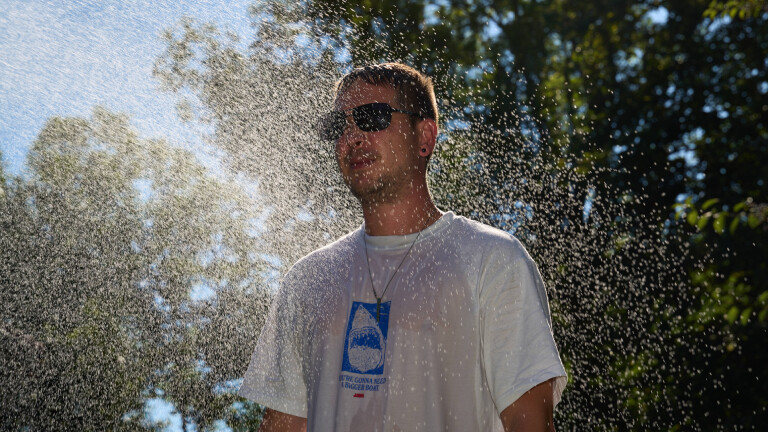 Ein Mann kühlt sich im Wassernebel ab