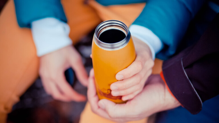 Eine wiederbefüllbare Flasche und drei Hände