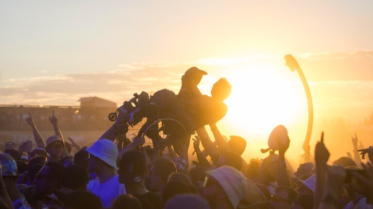 Ein Rollstuhlfahrer beim Crowdsurfen vor Sonnenuntergang beim Highfield Festival 2024.