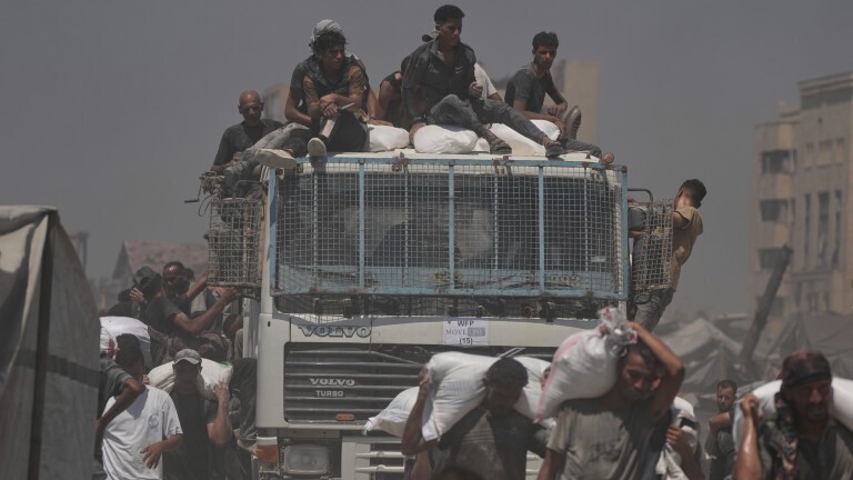 Palästinenser tragen Mehlsäcke, die von einem humanitären Hilfskonvoi abgeladen wurden, der Gaza-Stadt aus dem nördlichen Gazastreifen erreicht hat.