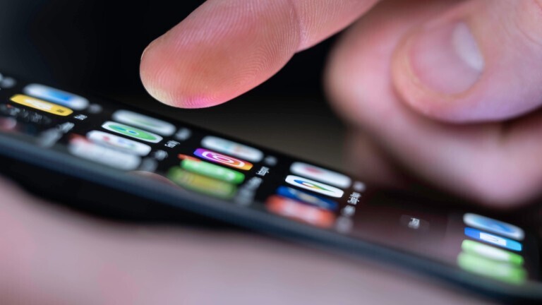 Eine Person tippt auf einem Handybildschirm verschiedene Apps an. Das Bild zeigt eine Nahaufnahme der Hand.