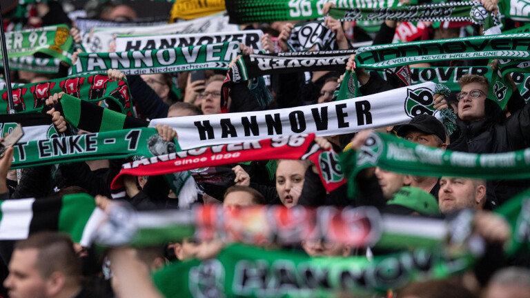 Hannover-Fans stehen im Oktober 2022 mit Schals auf der Tribüne