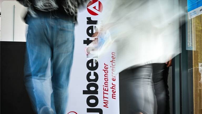 Personen gehen am Logo vom Jobcenter Berlin-Mitte bei der Jobmesse vorbei