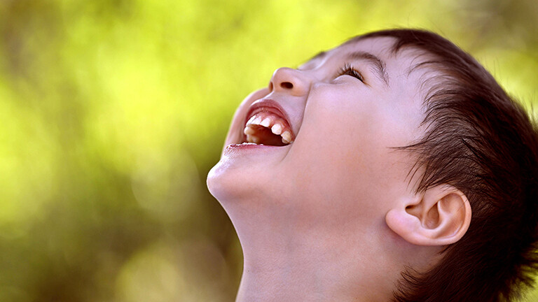 Foto eines kleinen Jungen der, herzlich lacht