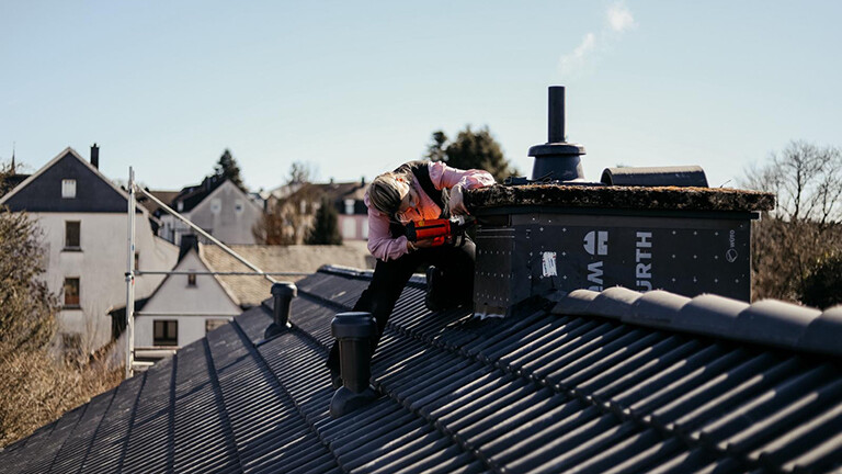 Foto der Dachdeckerin Lorelay Nova bei der Arbeit an einem Schornstein
