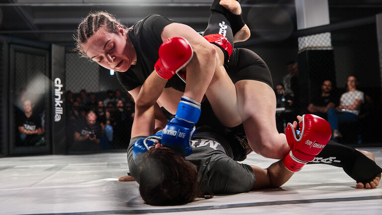 Zwei Kämpferinnen bei einem Mixed-Martial-Arts-Event in Berlin. Bei der Kampfsportart kämpfen die Frauen in einem achteckigen Käfig gegeneinander.