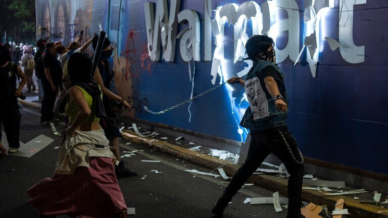 In Mexiko-Stadt zerstören vermummte Demonstranten den Werbe-Schriftzug "Walmart" während der zweiten Demonstration gegen Gentrifizierung.