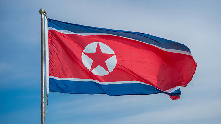 Foto einer Nordkorea-Flagge, die vor blauem Himmel im Wind flattert
