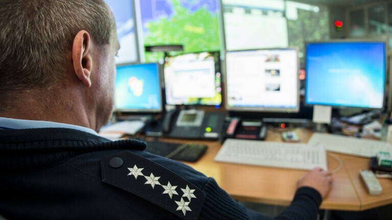 Ein Polizist arbeitet am Computer. Er ist von hinten zu sehen.