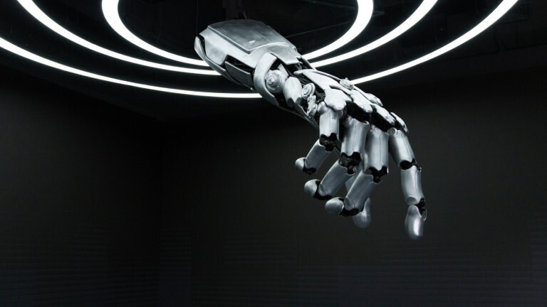 Eine Roboterhand ragt von oben aus Lichtkreisen hervor. Die Roboterhand zeigt nach unten.